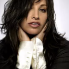 Black-haired woman in red lipstick, black outfit, white collar, and sparkling earrings