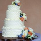 Three-Tiered Gold and Pink Floral Cake on Purple Background