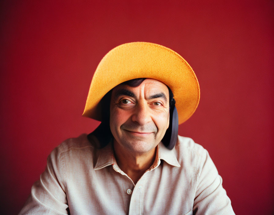 Smiling man in large yellow hat on red background