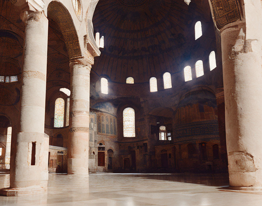 Historical building interior with arches, dome ceiling, and stained-glass windows.