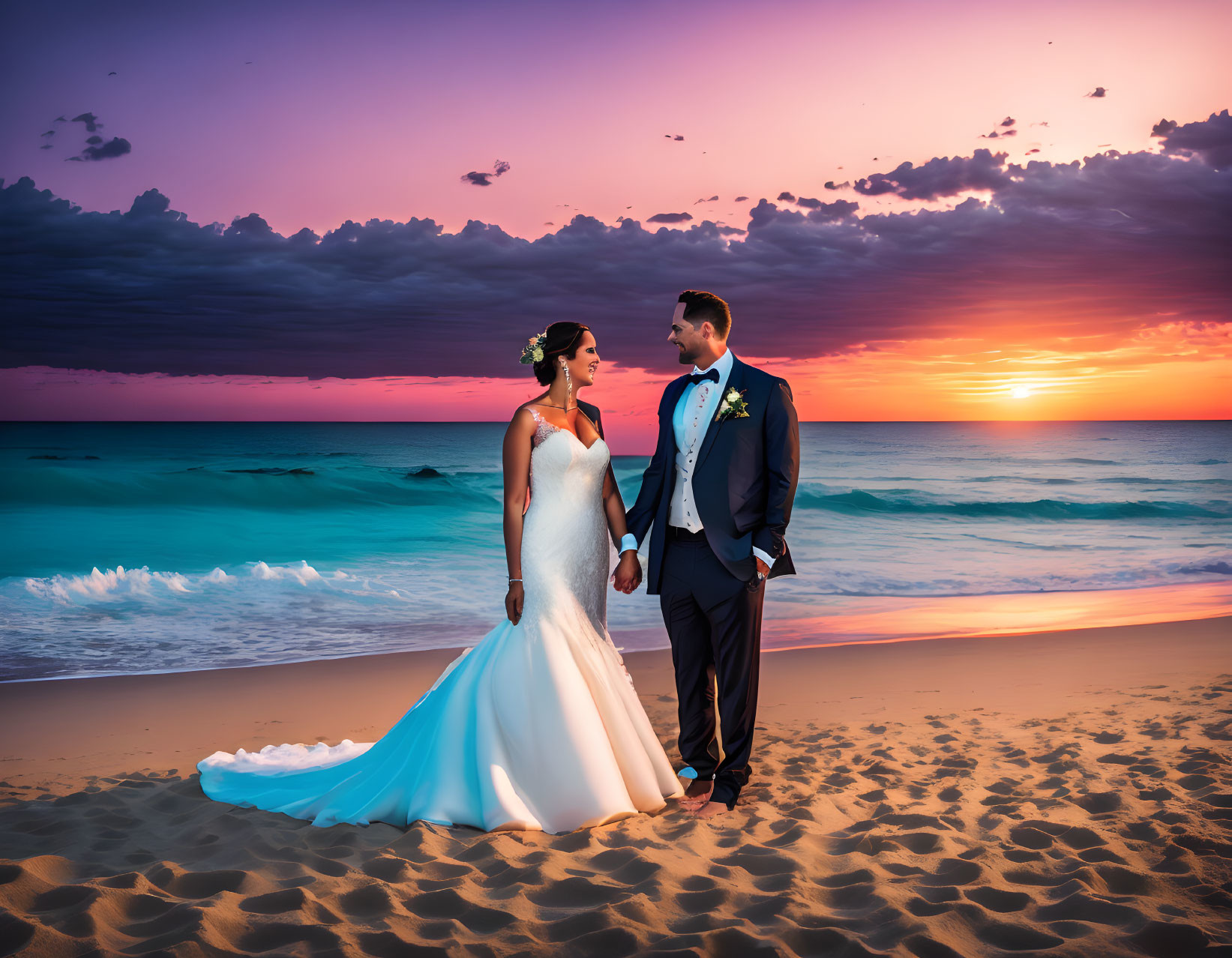 Wedding couple on beach at sunset with vibrant pink and blue skies