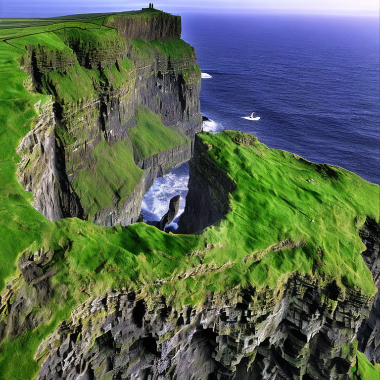 Scenic view of green cliffs, ocean, building, boat, and clear skies