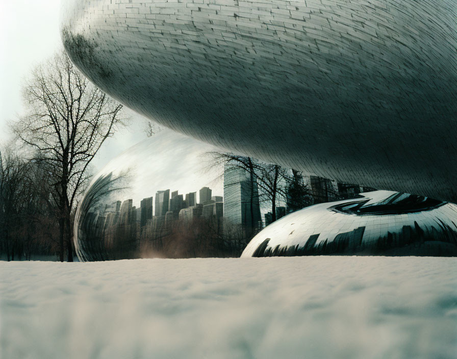 Reflective metallic structure towering over snowy cityscape.