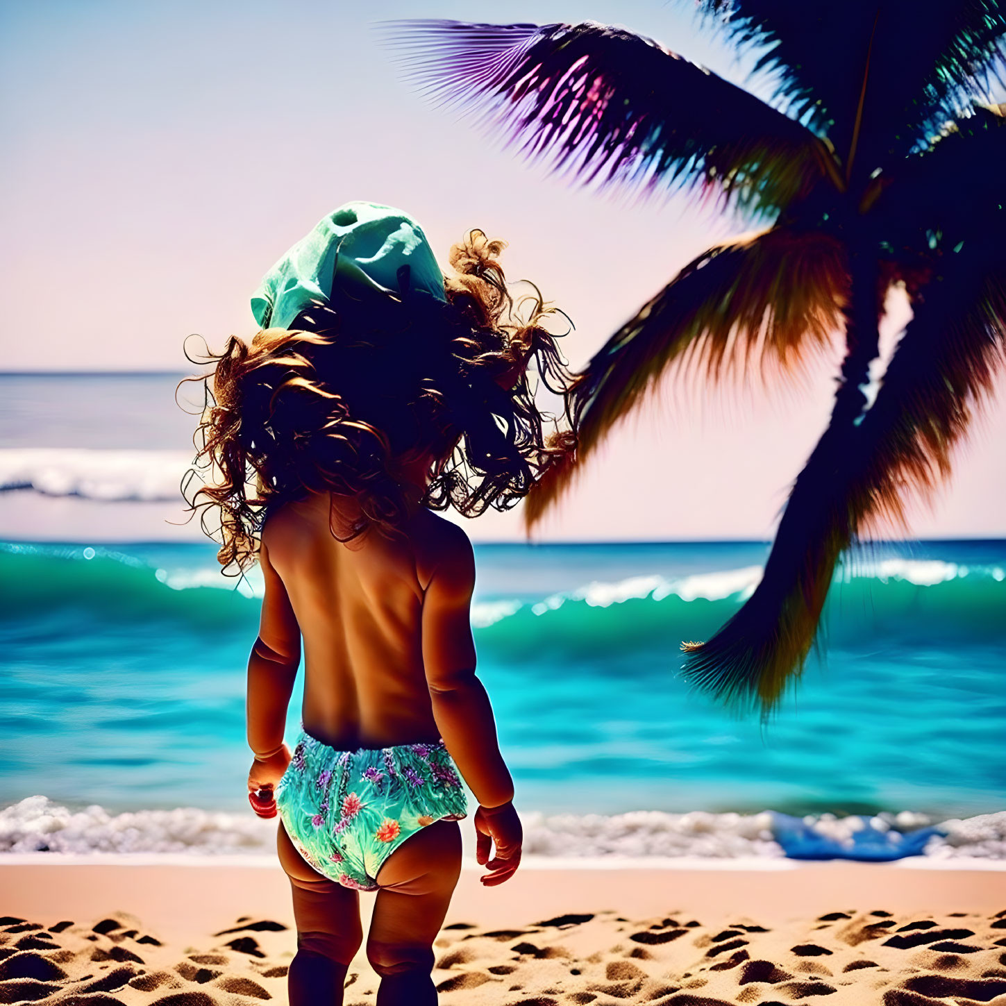 Curly-Haired Child in Hat and Swim Diaper on Sunny Beach with Palm Trees