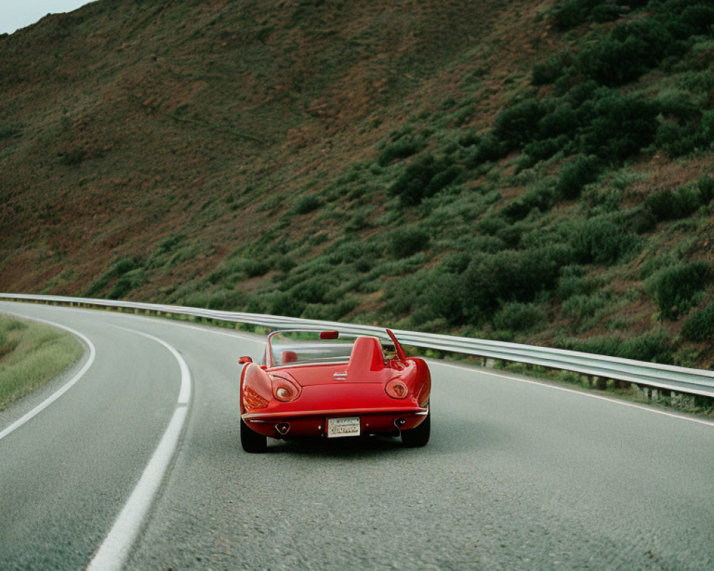 Classic Red Convertible Car on Curved Road with Green Hills Background