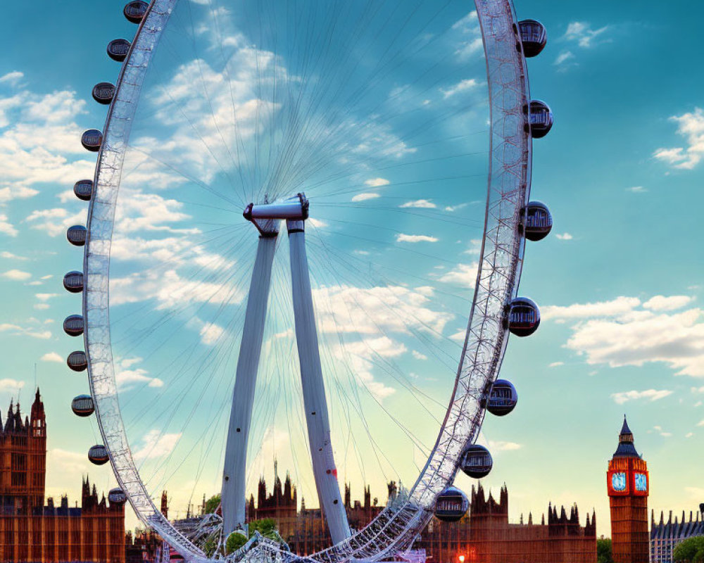 Observation wheel with enclosed capsules by river and historic buildings under blue sky