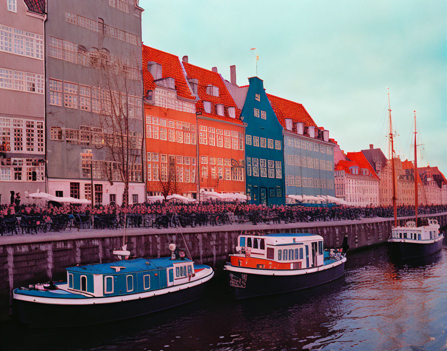 Traditional houses by vibrant canal with moored boats, cyclists, and soft sky