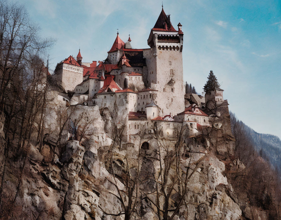 Majestic castle with high towers on craggy cliff in forested area