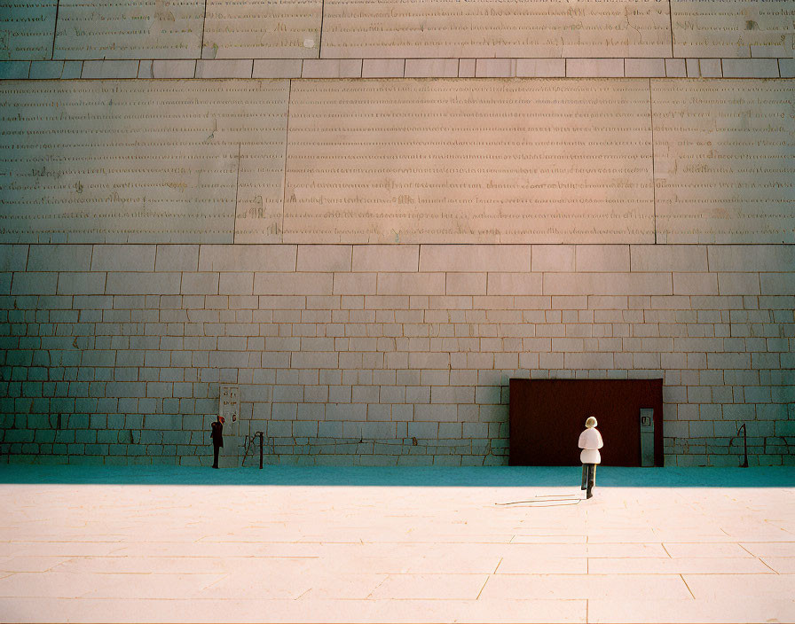 Solitary figure in front of grand stone-walled building with small dark entrance