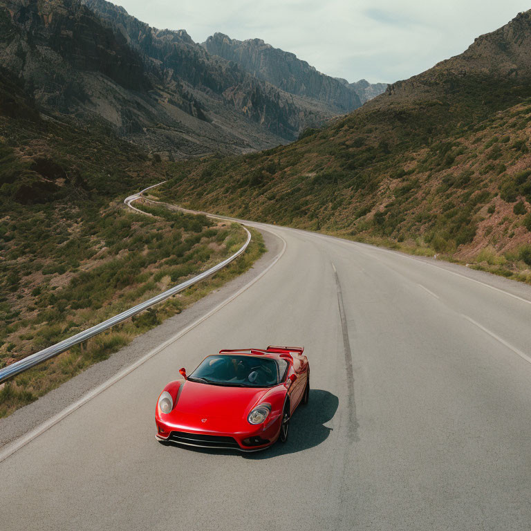 Red sports car parked on winding road with mountains and cloudy sky