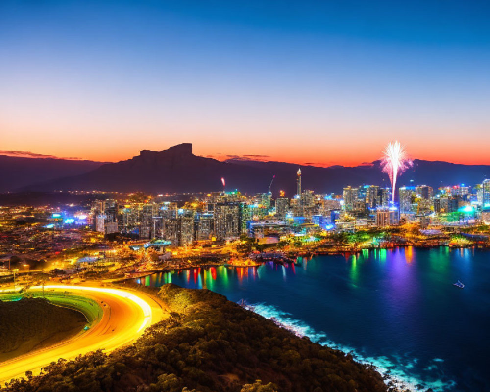 Night city skyline with fireworks, illuminated buildings, mountain backdrop, and reflective water.