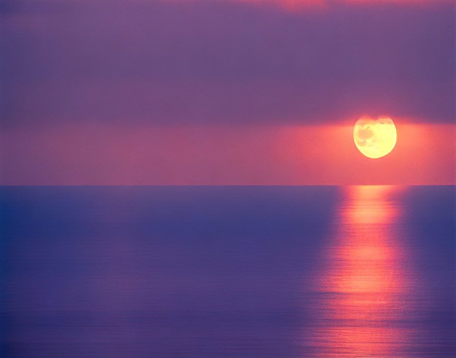 Tranquil sunset scene with purple and pink hues over calm sea