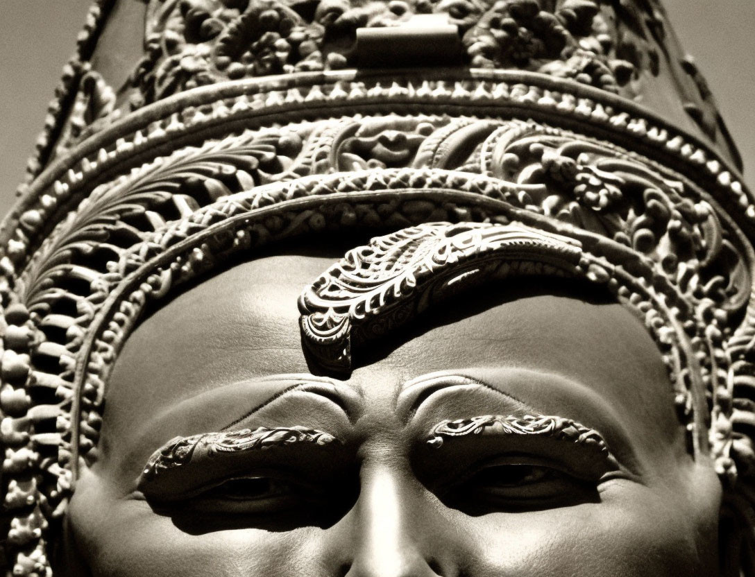 Detailed monochrome statue upper face with ornate crown and forehead decoration.