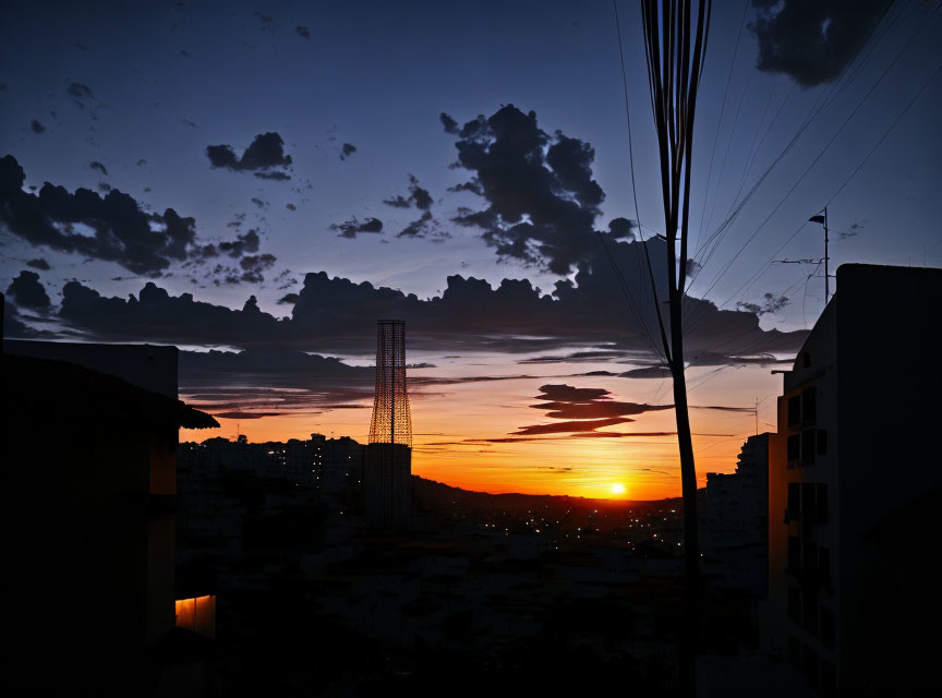 Vibrant Sunset Silhouetting Buildings and Tower in Orange Glow