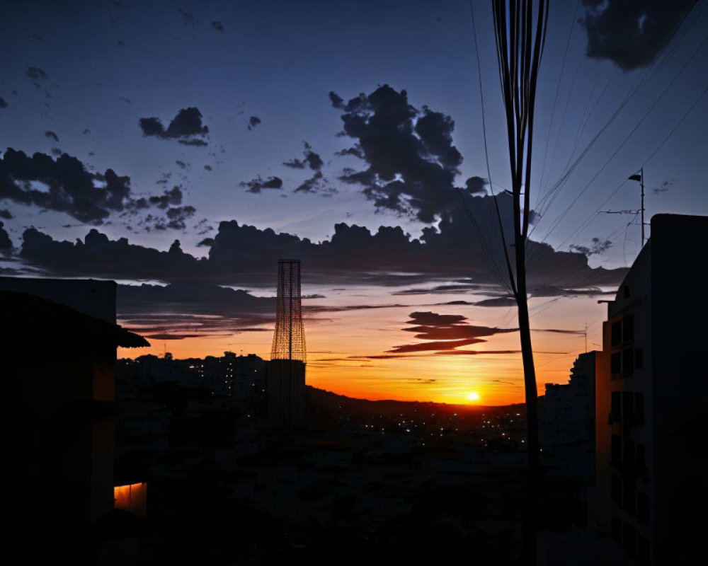 Vibrant Sunset Silhouetting Buildings and Tower in Orange Glow