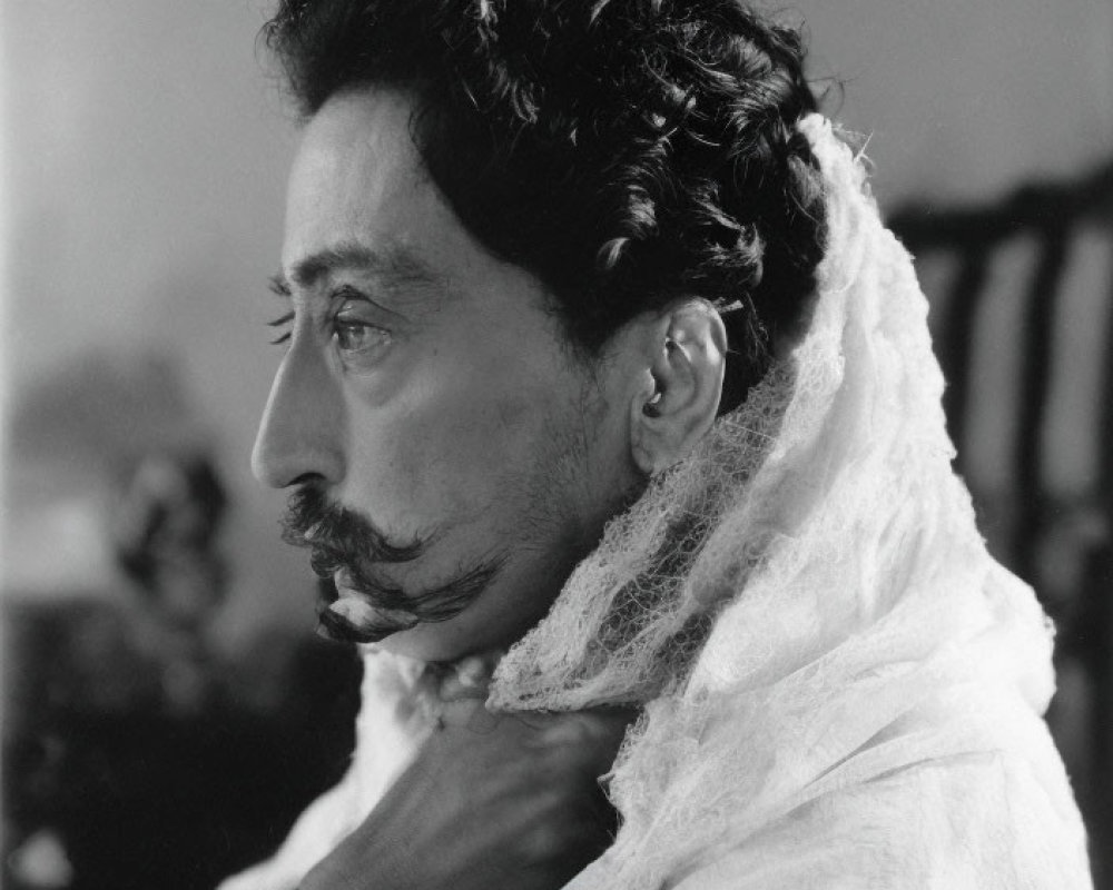 Monochrome profile portrait of a man with curly hair and thin mustache