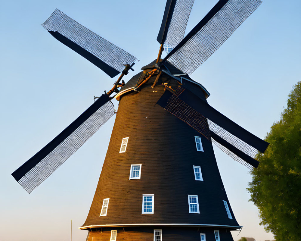 Traditional Wooden Windmill with Large Lattice Sails at Sunrise or Sunset