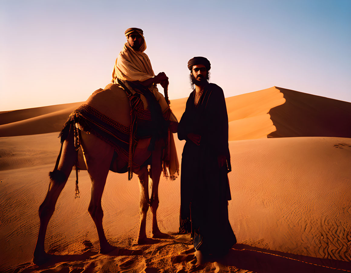 Men in traditional attire with camel in desert at sunset