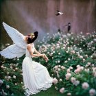 Angel-winged woman in white dress surrounded by pink and white flowers in mystical garden.