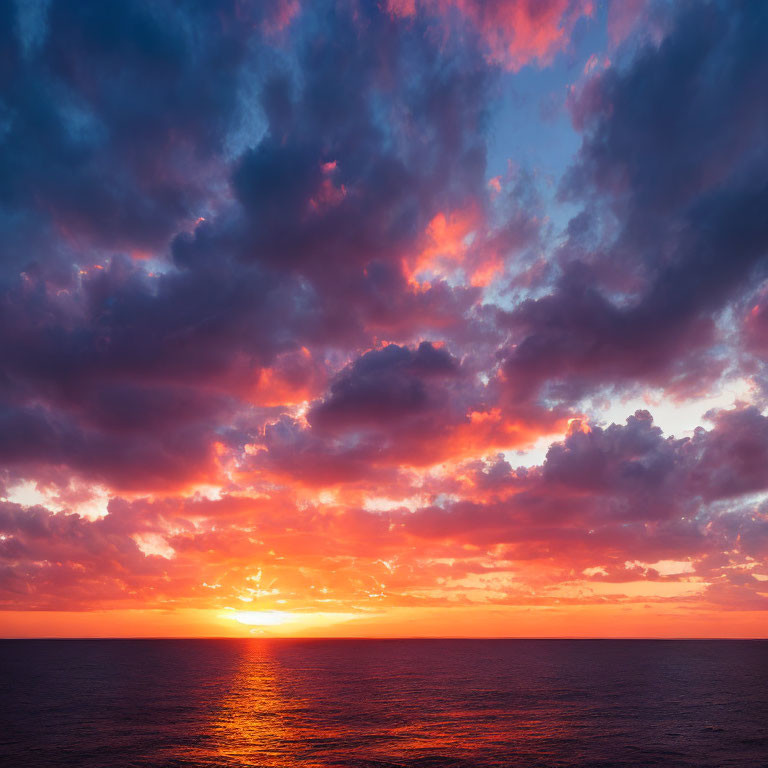 Dramatic sunset with fiery orange and pink hues over calm ocean horizon