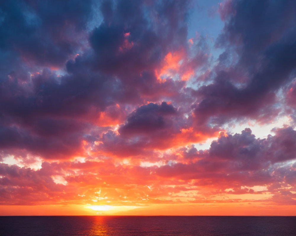 Dramatic sunset with fiery orange and pink hues over calm ocean horizon