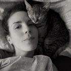 Monochrome image of woman with cats resting on her chest