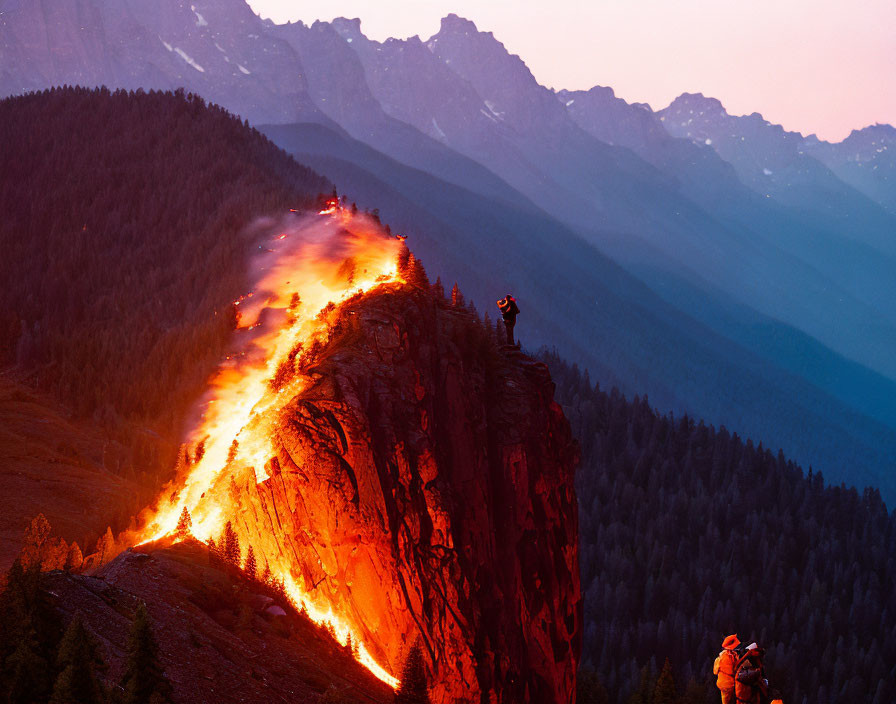 Wildfire consumes mountainside at dusk with firefighters and bystander.