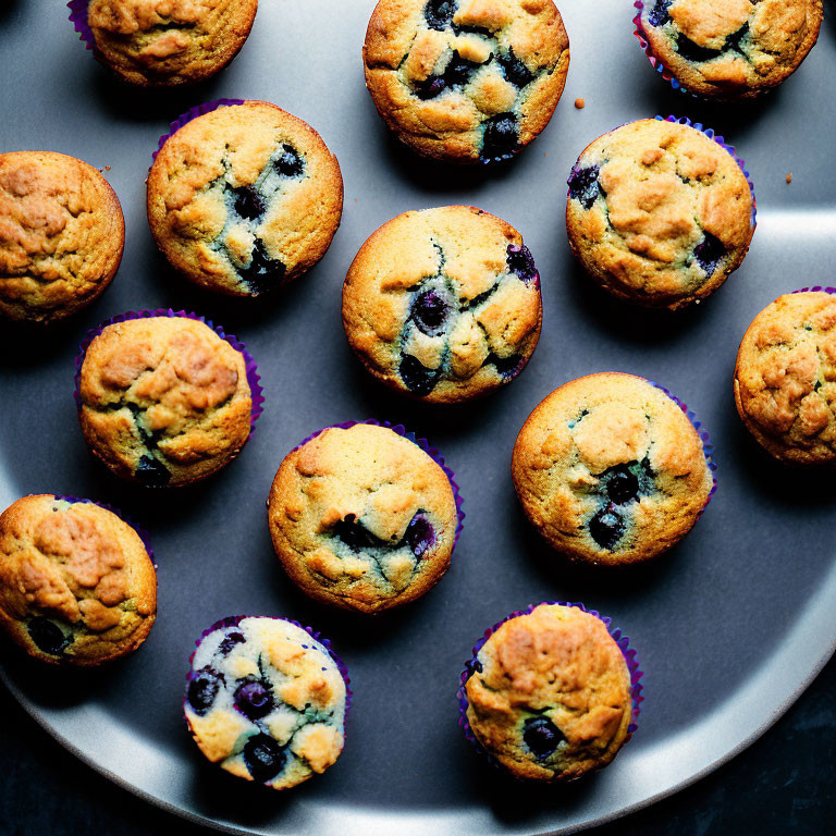 Freshly Baked Blueberry Muffins in Purple Liners on Dark Tray