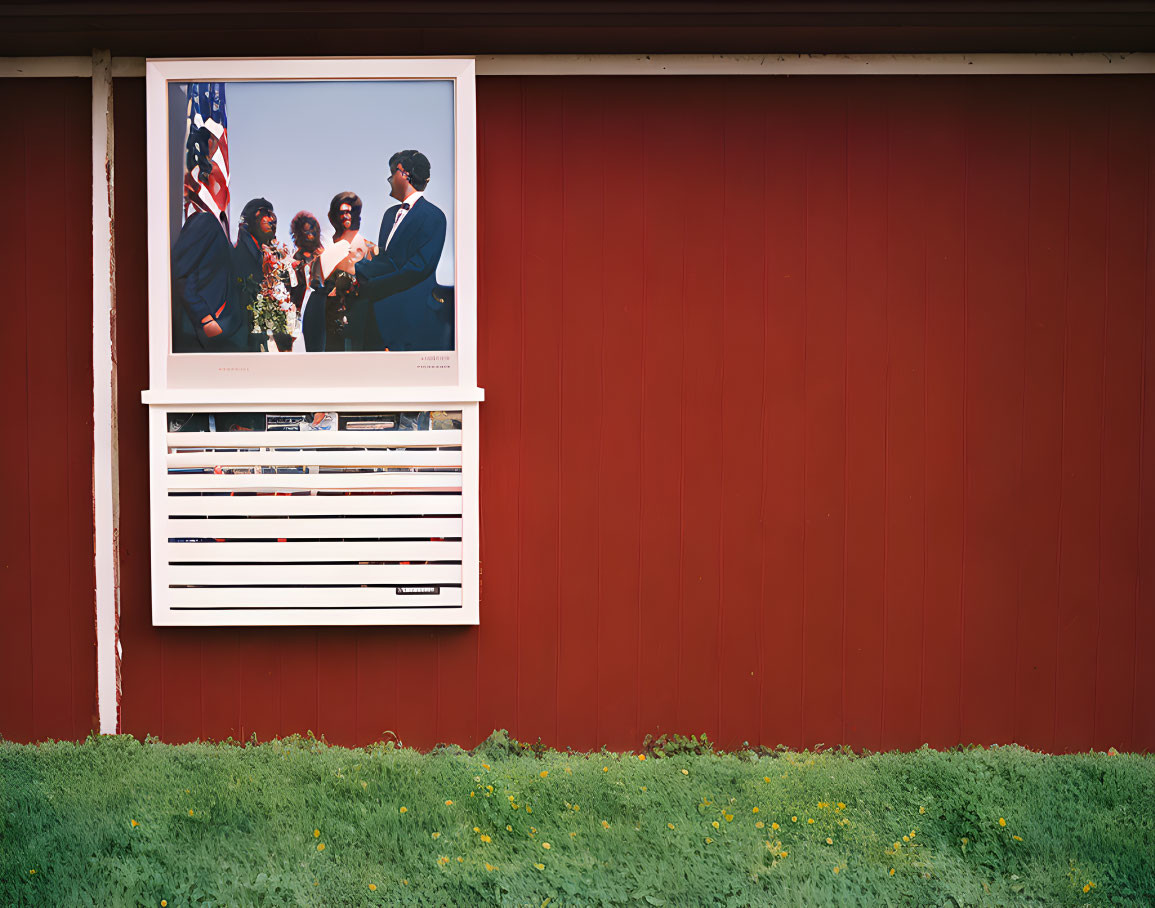 Ceremony photo on red wall with green shrubbery