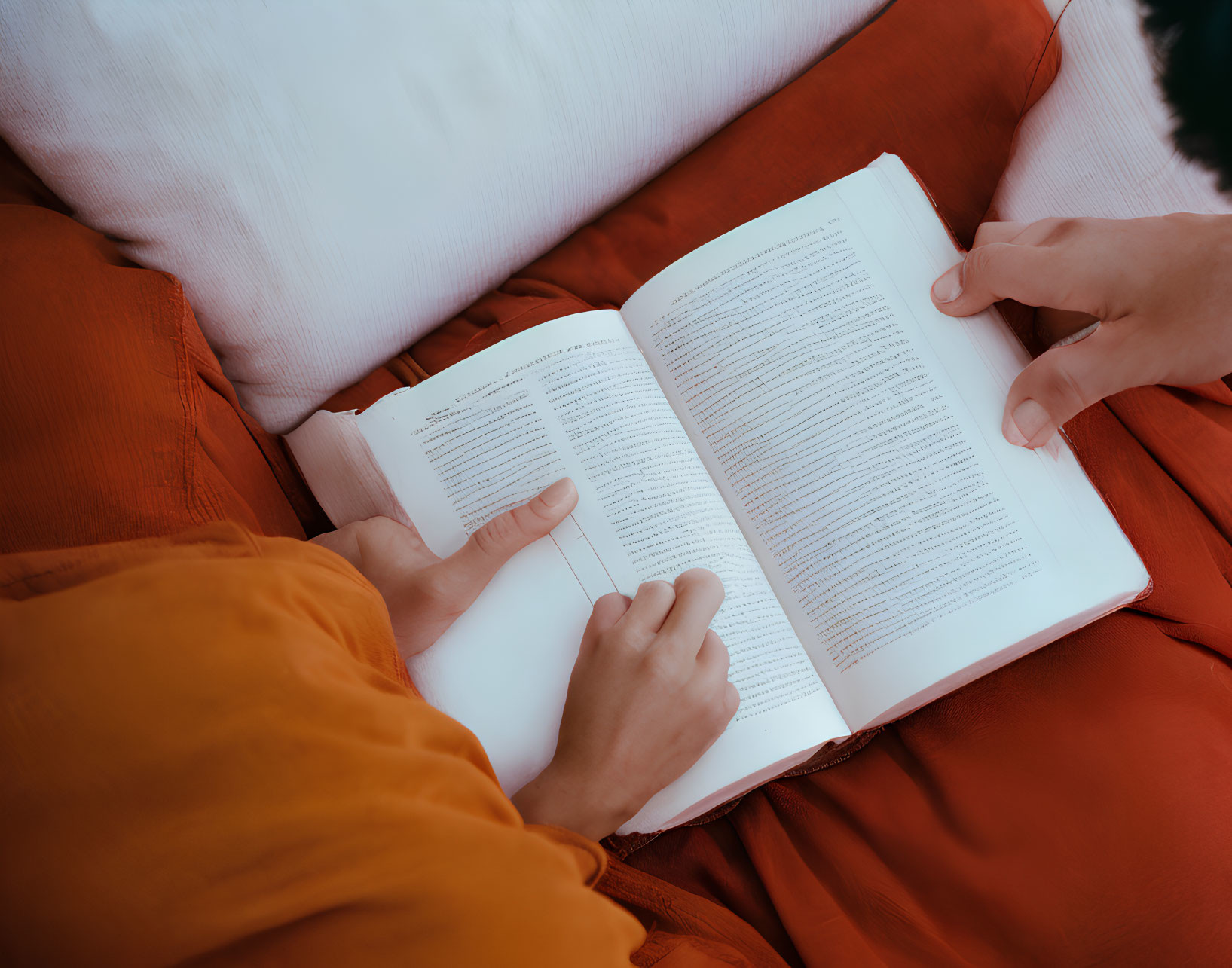 Person in Orange Outfit Reading Book on Red Background