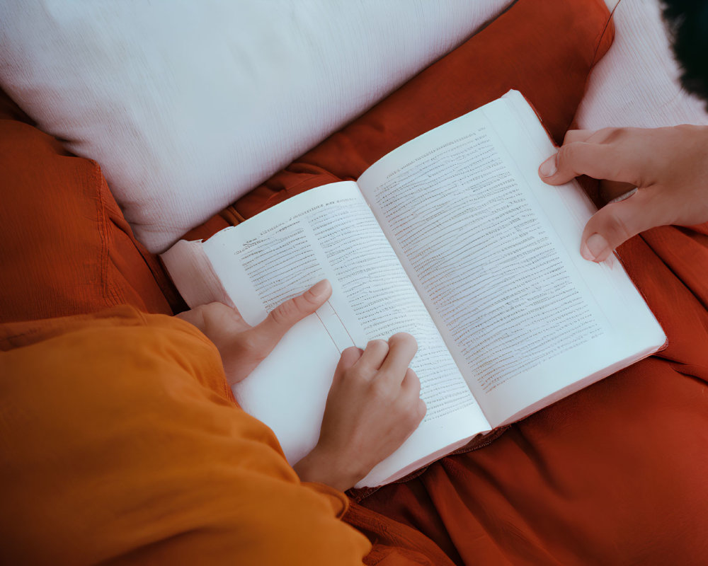 Person in Orange Outfit Reading Book on Red Background