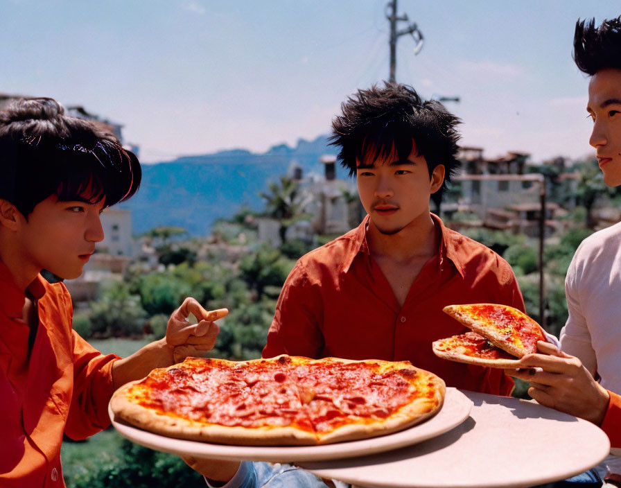 Three people eating pizza outdoors with greenery and mountains.