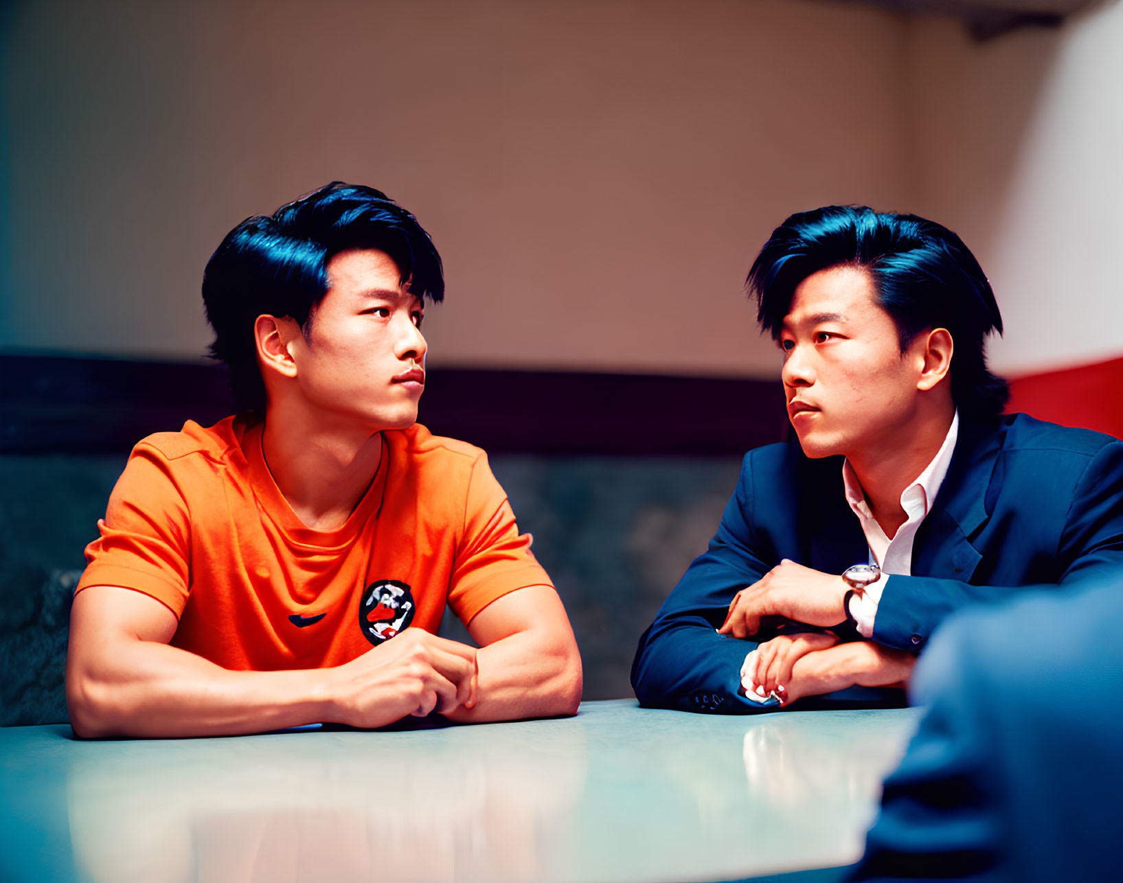 Men in Orange Shirt and Business Suit Engaged in Serious Conversation