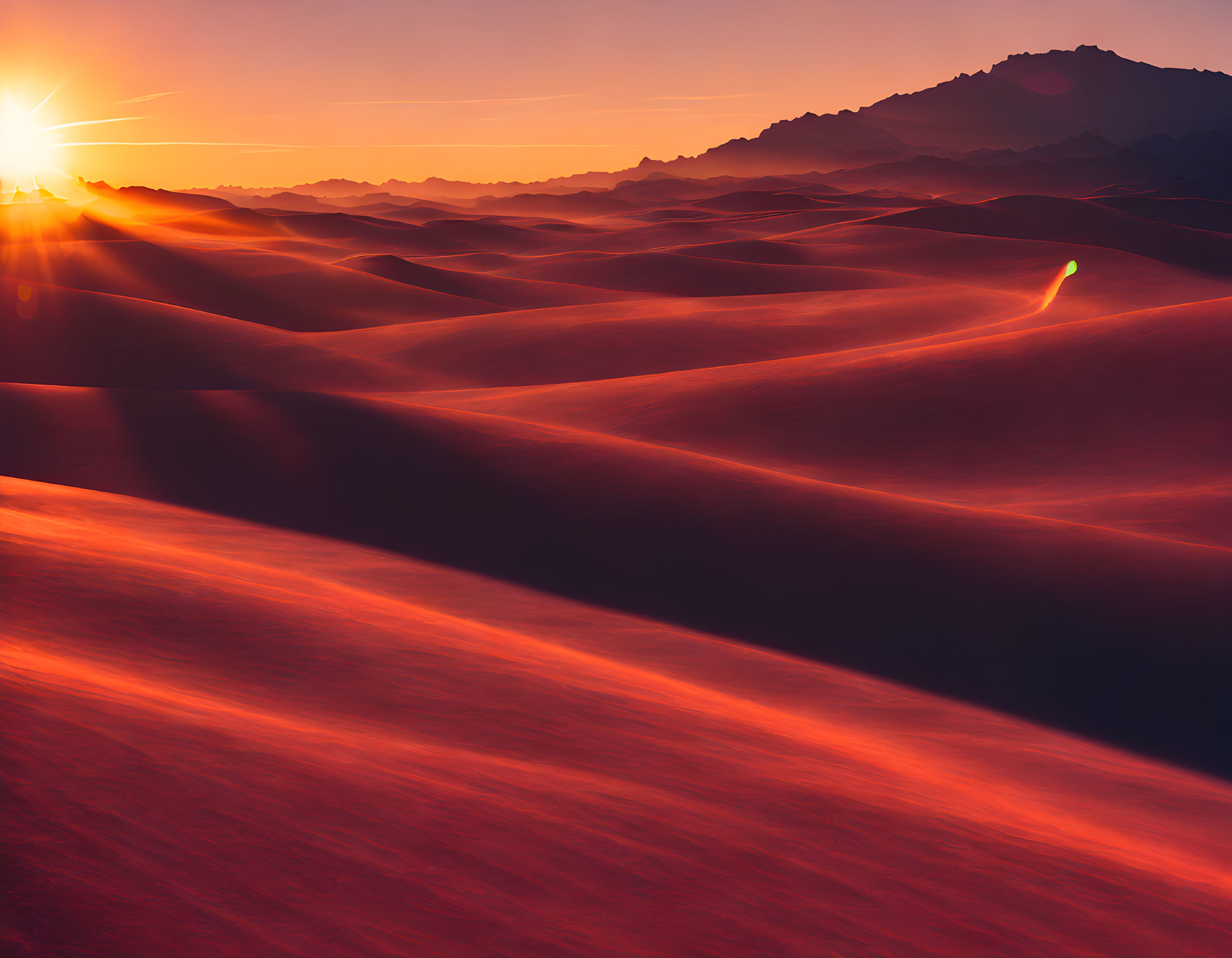 Vibrant sunset illuminating sand dunes with textured shadows