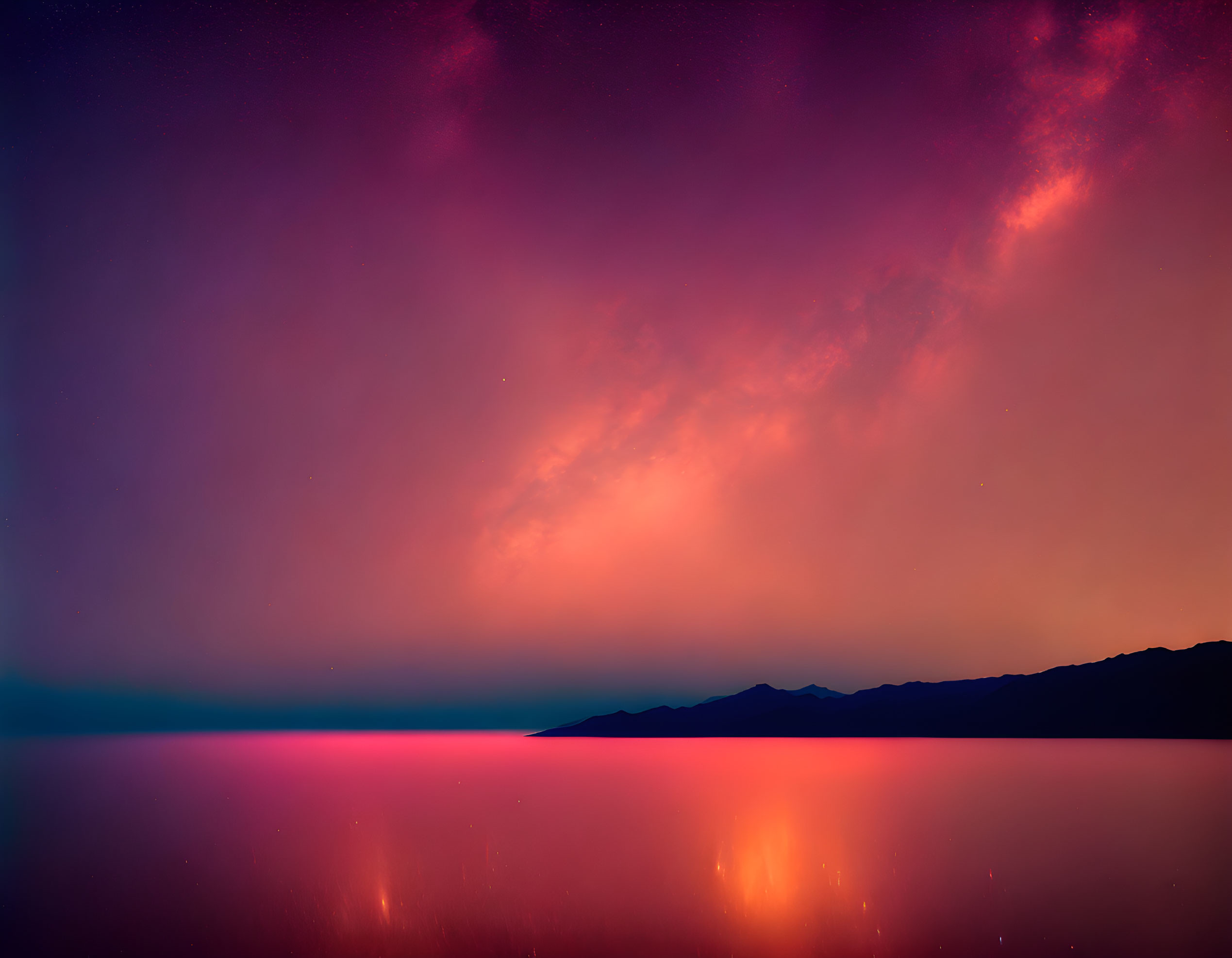 Twilight sky with purple and pink hues over tranquil water and mountain silhouette