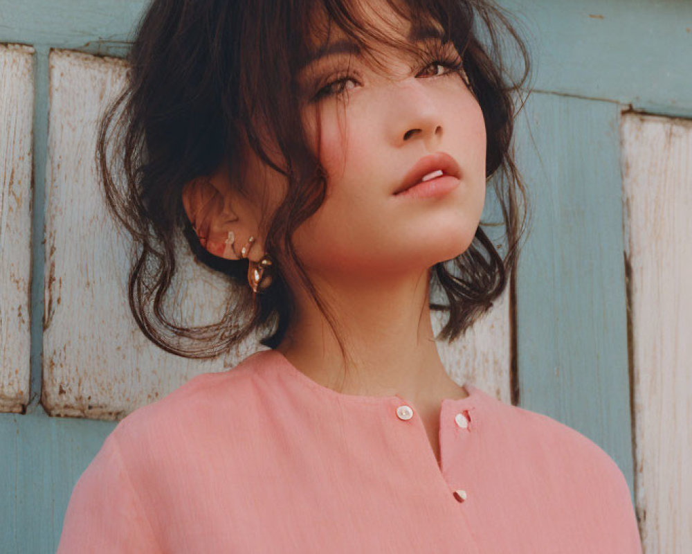 Woman with Shoulder-Length Hair in Pink Blouse on Blue Wooden Background