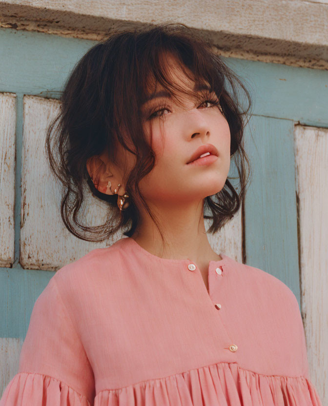 Woman with Shoulder-Length Hair in Pink Blouse on Blue Wooden Background