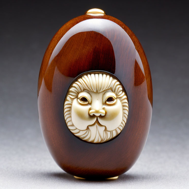 Intricately Carved Oval Object with Stylized Face and Golden Accents