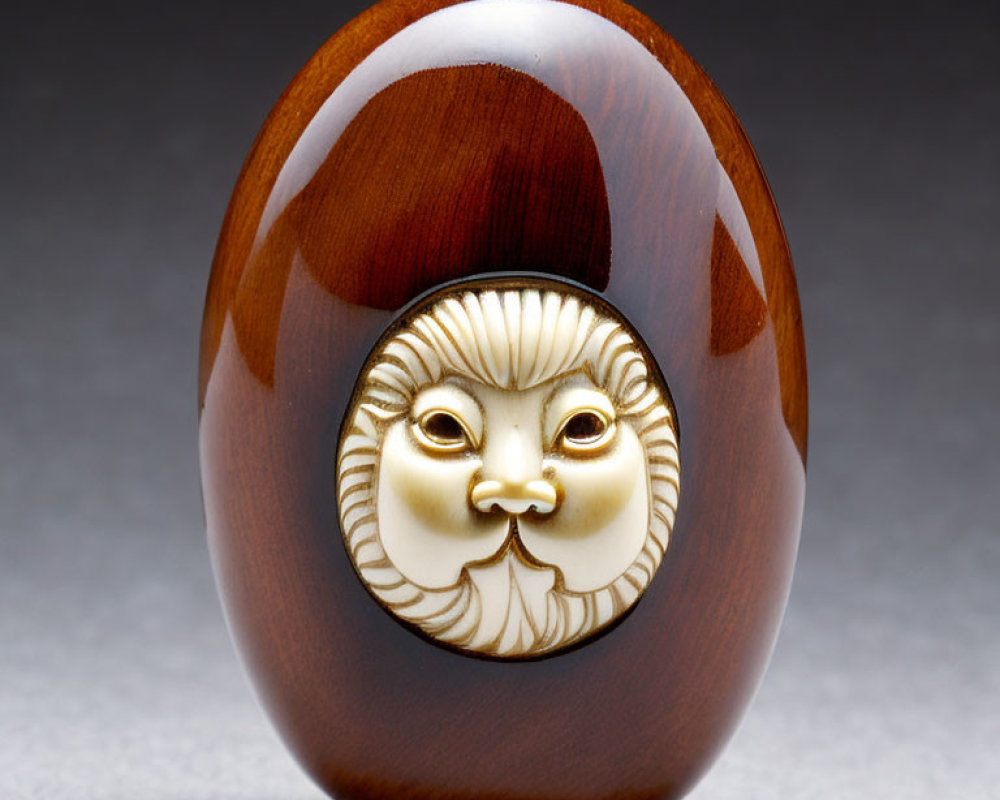 Intricately Carved Oval Object with Stylized Face and Golden Accents