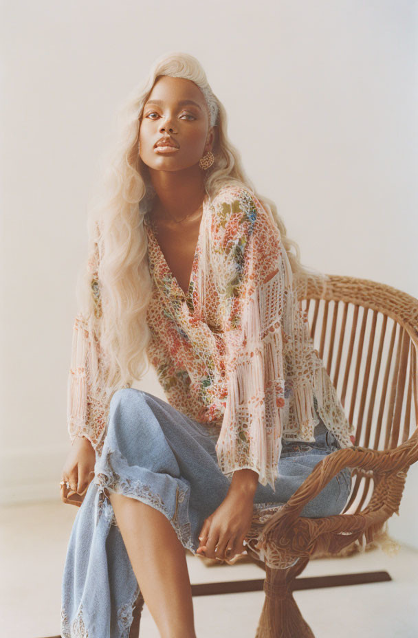 Woman with Wavy Hair Sitting on Rattan Chair in Softly Lit Room