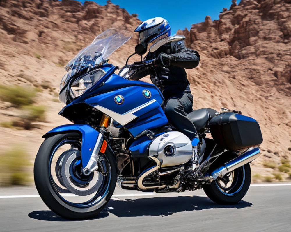 Motorcyclist in full gear riding BMW touring bike on sunny day in rocky desert.