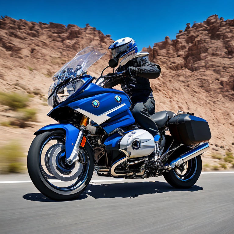 Motorcyclist in full gear riding BMW touring bike on sunny day in rocky desert.