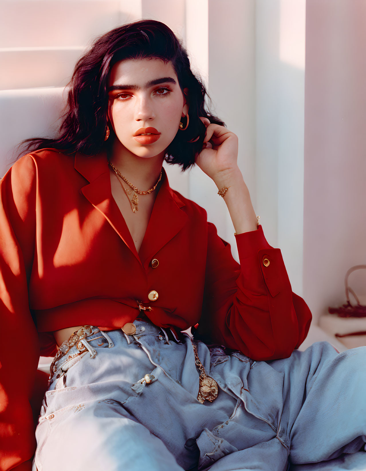 Woman in Red Blouse and Blue Jeans Poses in Soft Sunlight