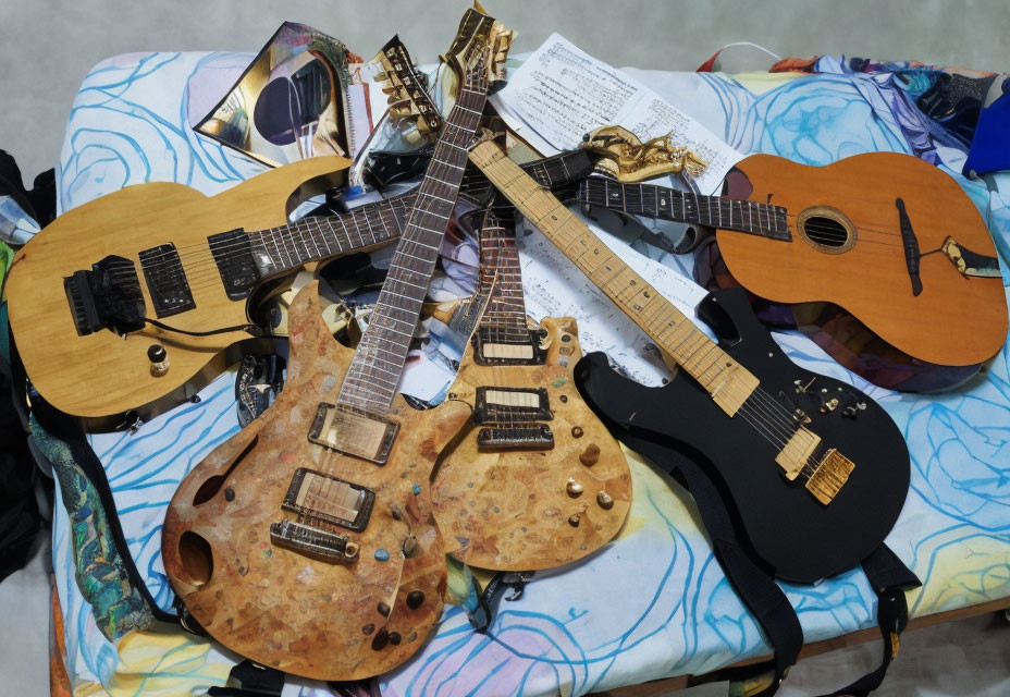 Assorted guitars and sheet music on bed.