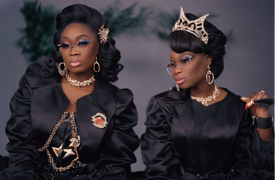 Two women in elegant black dresses with gold accessories posing confidently