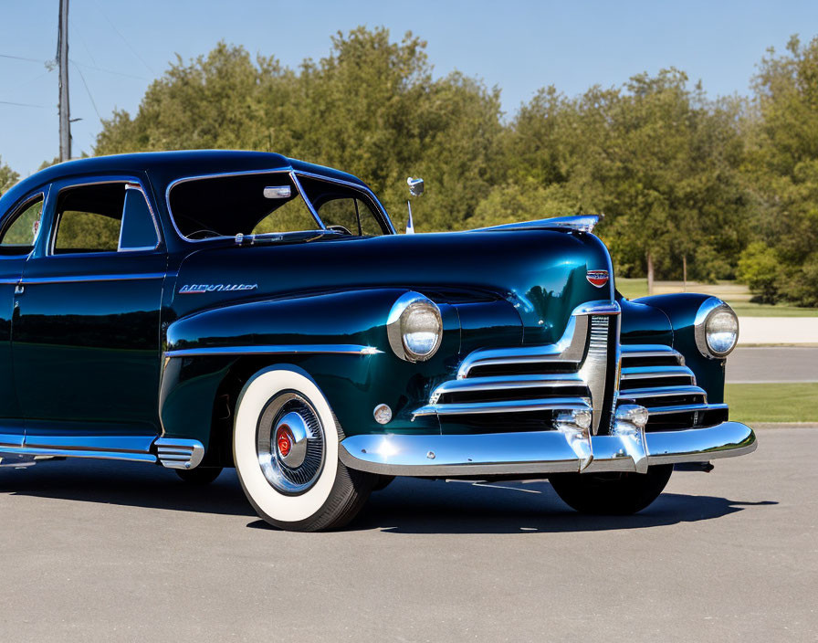 Vintage blue Chevrolet parked on asphalt with white wall tires