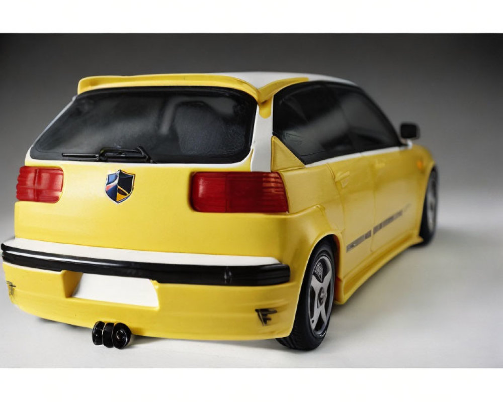 Yellow Toy Sporty Hatchback Car Model with Graphics and Dual Exhaust on White Background