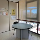 Hospital room with medical equipment, round table, chair, and cityscape view