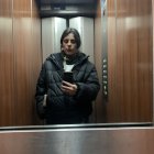 Young woman in elevator with clipboard under soft lighting