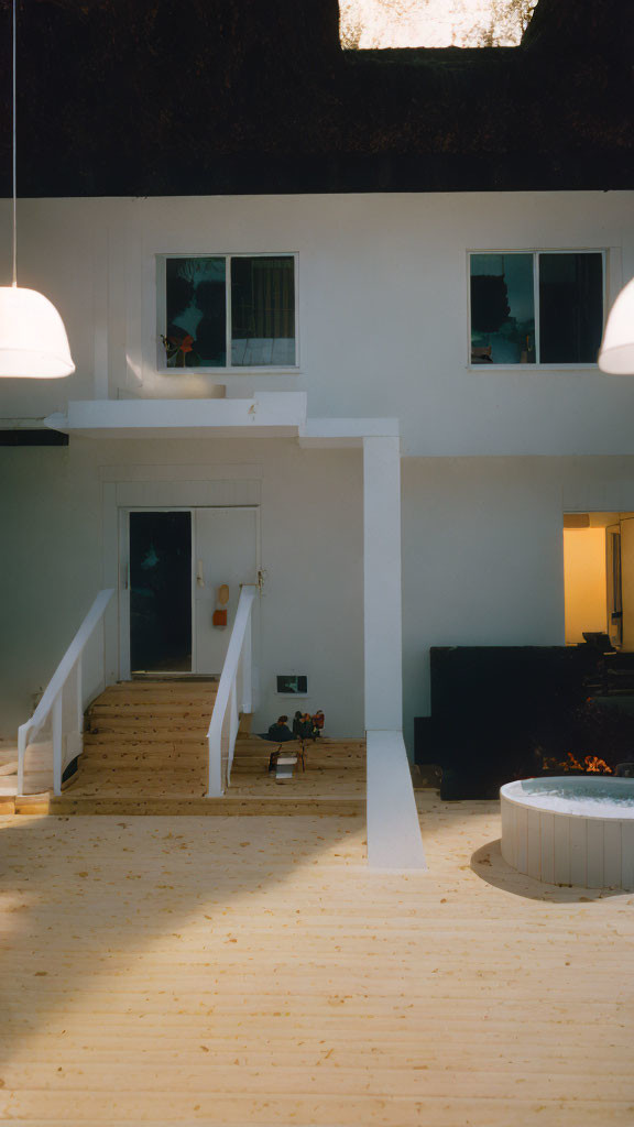 Two-story home interior with open staircase, light wood floors, white walls, hanging lights, and warmly